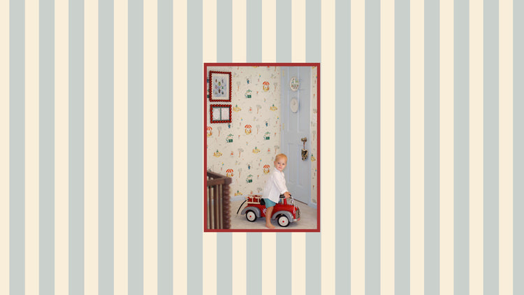 toddler boy riding a red car with blue door and parks illustrated wallpaper. blue stripe wallpaper
