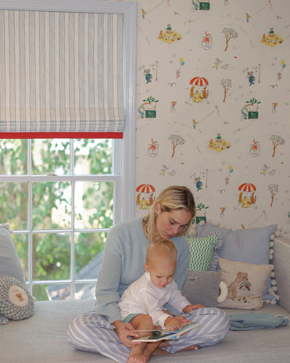 Woman reading to a child on a couch with colorful wallpaper and window blinds in the background