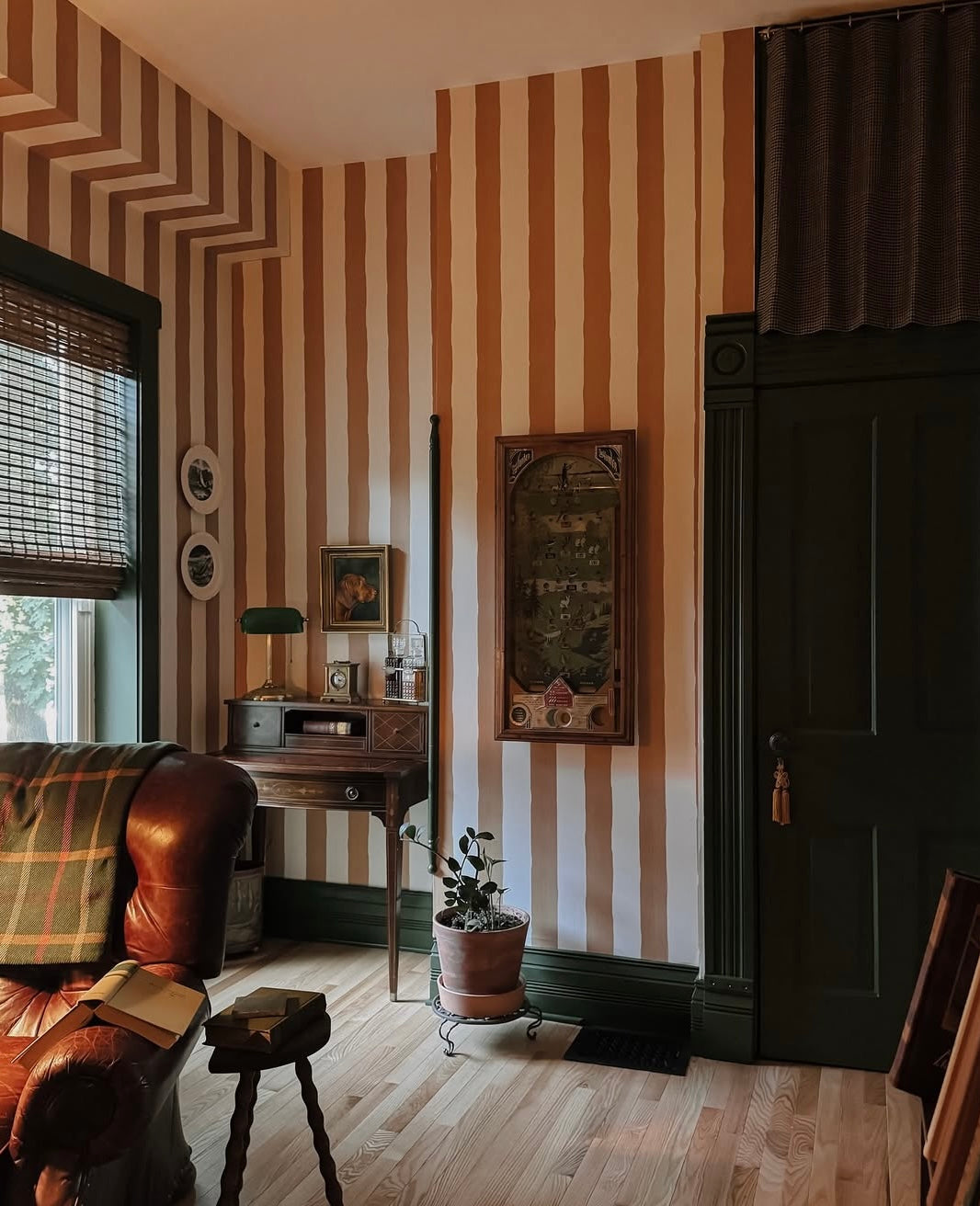 Vintage-style room with striped walls, leather sofa, and wooden furniture.