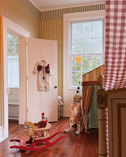 Children's room with wooden floor, toys, and a checkered curtain.