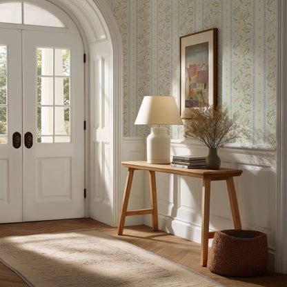 Narrow hallway with a wooden side table, lamp, and decorative items against a wall with framed art.
